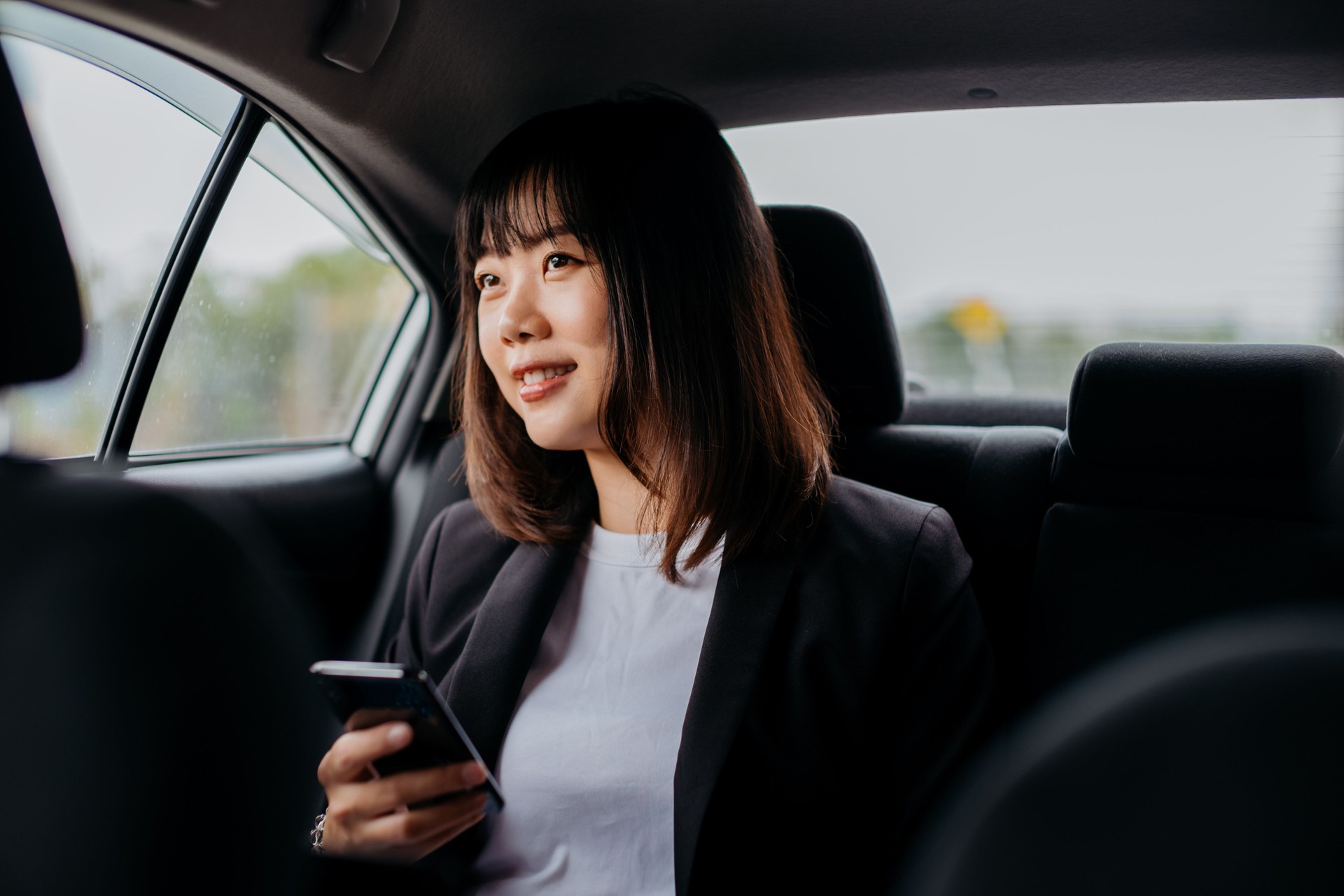 Jeune femme d’affaires asiatique utilisant le smartphone dans la voiture